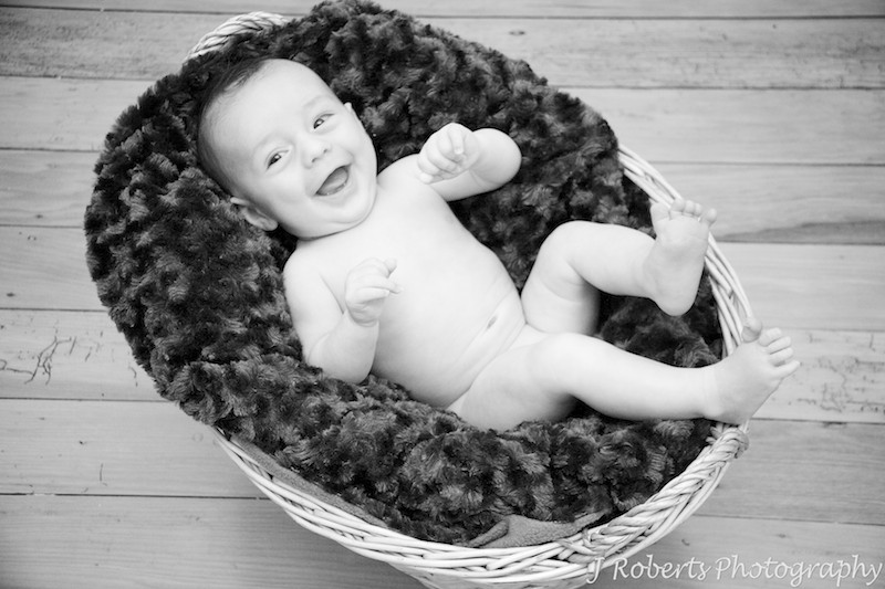 Laughing naked baby in basket - baby portrait photography sydney